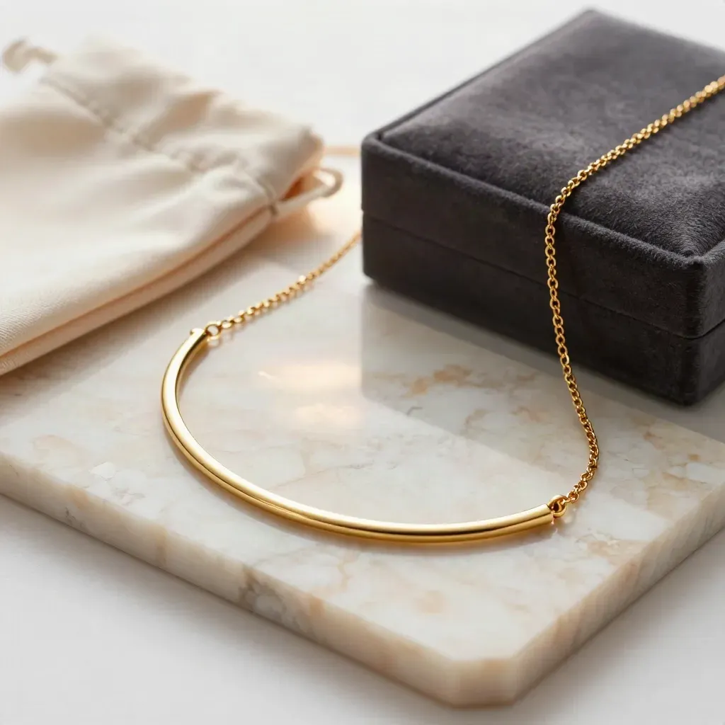 Collier or courbé sur pierre claire avec écrin sombre et reflets élégants.